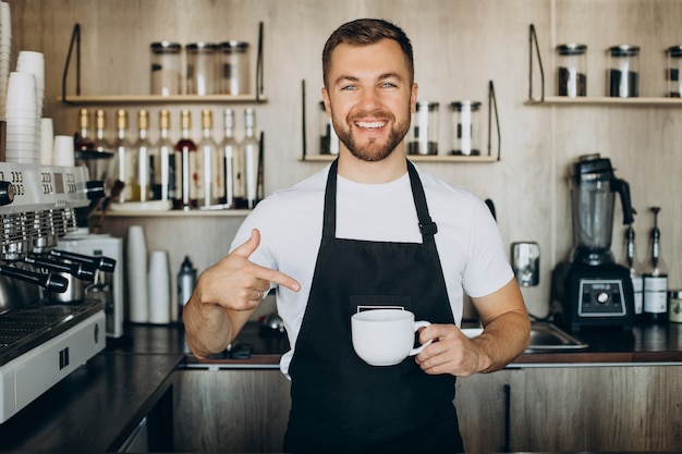 maennlicher-barista-im-cafe-mit-tasse-an