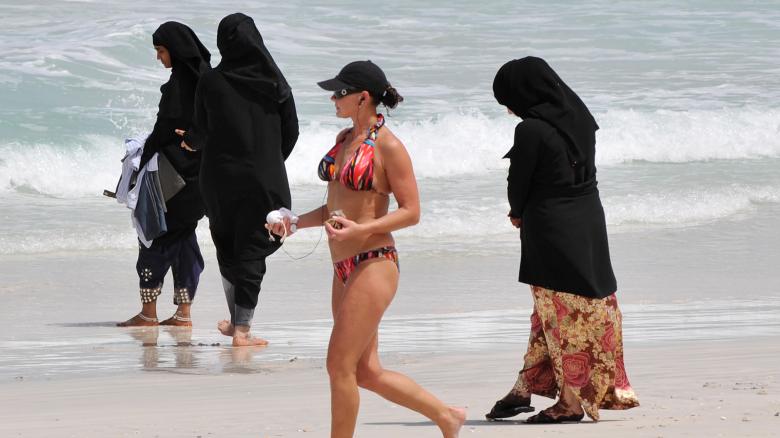 A-woman-in-a-bikini-walks-past-a-lady-in